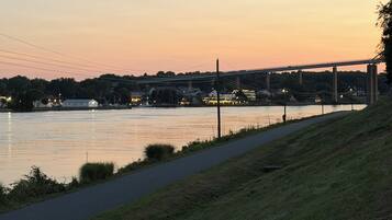 A riverside walkway with a bridge in the background.