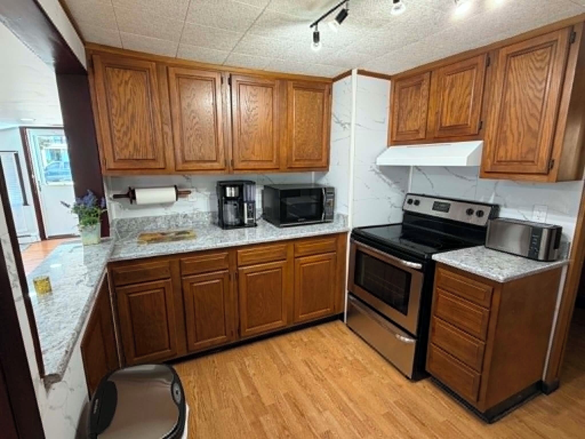 A kitchen with wooden cabinets, a microwave, a stove, and a coffee maker.