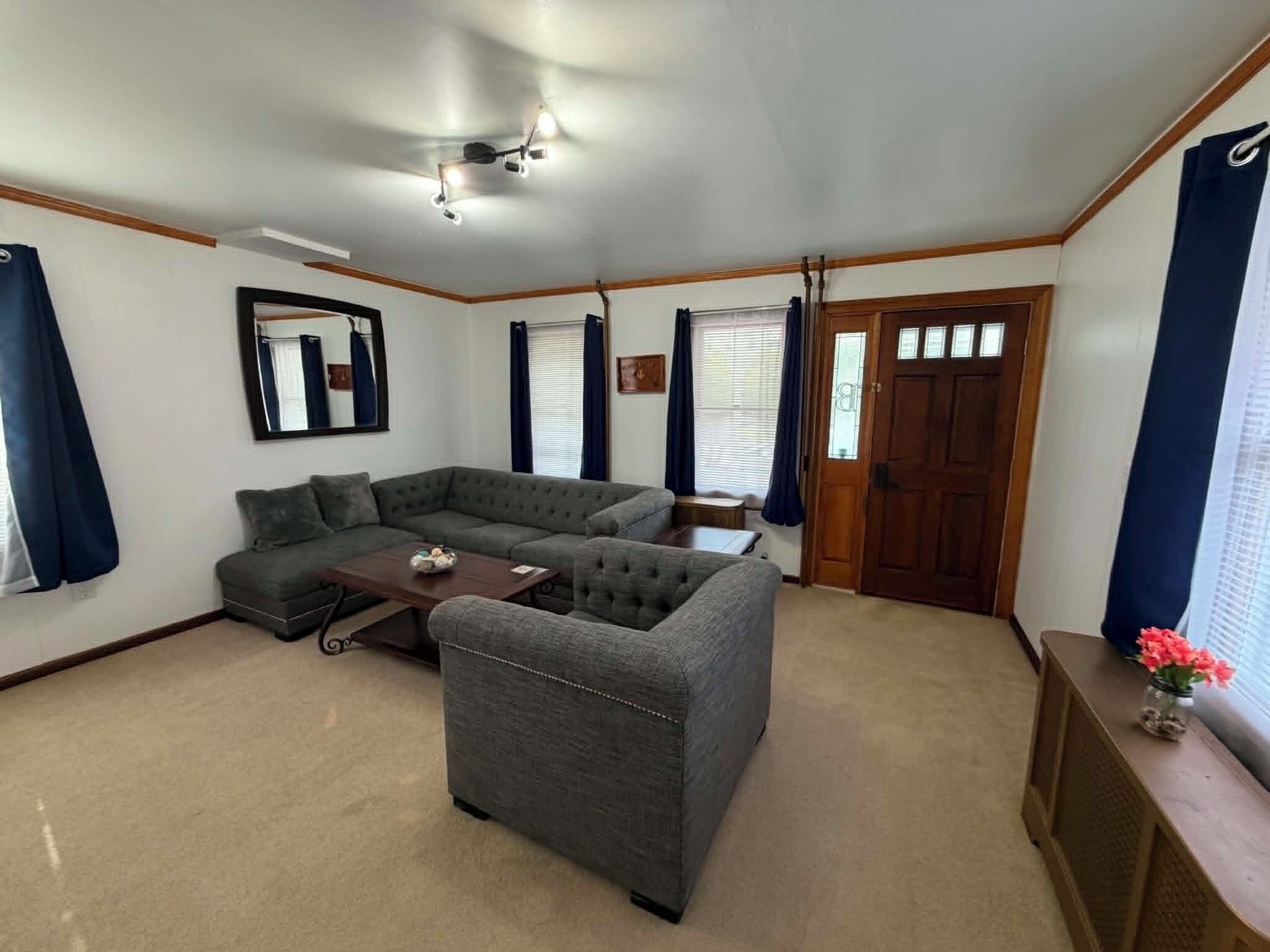 A living room with a sectional sofa, a coffee table, a ceiling fan, and a door with a window.