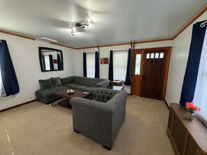 Una sala de estar con un sofá modular, una mesa de centro, un ventilador de techo y una puerta con ventanal.