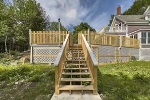 A wooden staircase leading to a gated area with a house in the background. - The Owl's Roost Manor in Owl's Head, ME (Owls Head)
