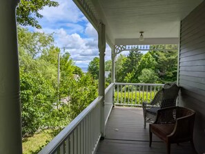Een overdekte veranda met uitzicht op een groen landschap en heldere lucht.