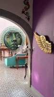 A room with a purple wall, a decorative archway, a winged sculpture, and a patterned floor.