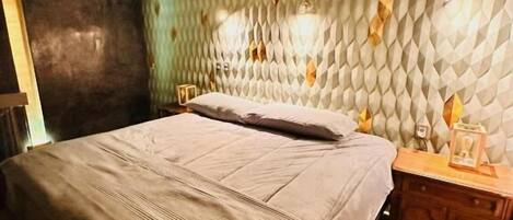 A bedroom with a bed, a nightstand, and a wall with a textured pattern.