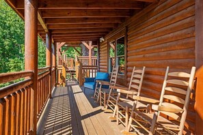 Eine Holzhütte mit Veranda, Holzstühlen und einer Bank.