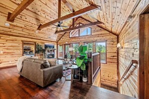 L’intérieur d’une cabane en rondins, avec un canapé, une table à manger et une cheminée.