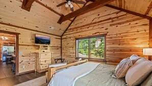 A wooden cabin bedroom with a bed, a desk, and a television. - Sleeps ~22, Heated Indoor Pool, Hot Tub, Game Room (Sevierville)