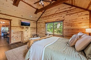 Ein Schlafzimmer einer Holzhütte mit einem Bett, einem Schreibtisch und einem Fernseher.