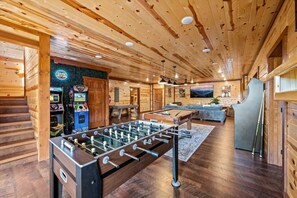 A wooden-floored room with a foosball table, a pool table, and a bar area with arcade machines. - Sleeps ~22, Heated Indoor Pool, Hot Tub, Game Room (Sevierville)