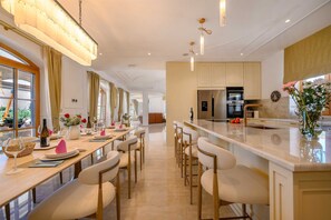 A modern kitchen with a central island, bar seating, and a dining area with a long table. - Beachfront Villa Adriatic Z with Pool (Žaborić)