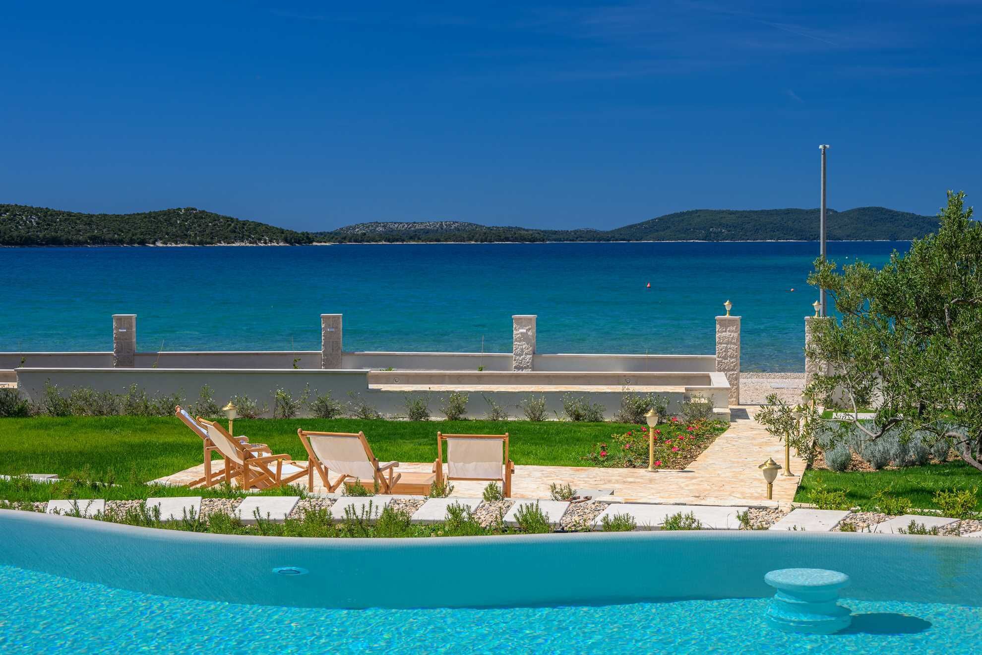 Zona de piscina con sillones y vista al mar.