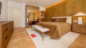 Quarto com uma cama grande, um banco, cômoda e mesa de cabeceira.