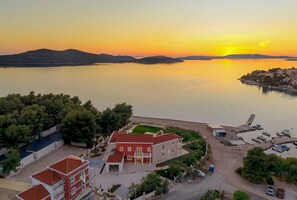 A coastal property with a marina, a red-roofed house, and a clear view of the sunset over the water. - Beachfront Villa Adriatic Z with Pool (Žaborić)