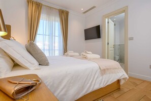 A hotel room with a bed, a TV mounted on the wall, a bathroom visible through an open door, and a wooden floor. - Beachfront Villa Adriatic Z with Pool (Žaborić)