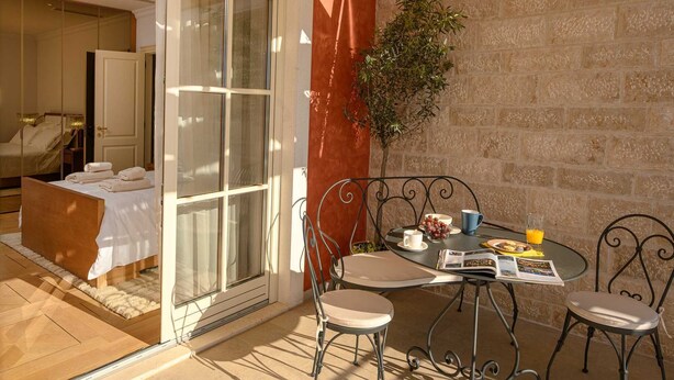 Quarto com cama, mesa com itens de café da manhã e vista para um jardim.