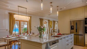 Uma cozinha moderna com uma ilha central, eletrodomésticos de aço inoxidável e vista para o mar.