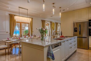 A modern kitchen with a central island, stainless steel appliances, and a view of the sea. - Beachfront Villa Adriatic Z with Pool (Žaborić)
