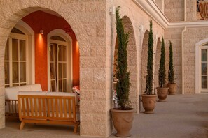 A stone building with a wooden bench, potted evergreen trees, and arched doorways. - Beachfront Villa Adriatic Z with Pool (Žaborić)