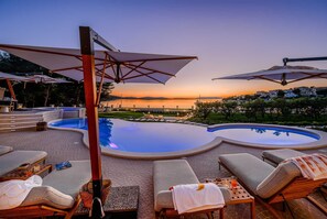 A poolside area with lounge chairs, umbrellas, and a view of the sunset over a body of water. - Beachfront Villa Adriatic Z with Pool (Žaborić)