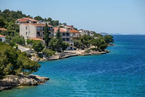 A coastal town with buildings along the water, clear skies, and a view of the sea. - Villa Between Seas with Pool (Ražanj)