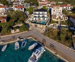 A coastal residential area with modern houses, a marina with several boats, and a clear blue sea. - Villa Between Seas with Pool (Ražanj)