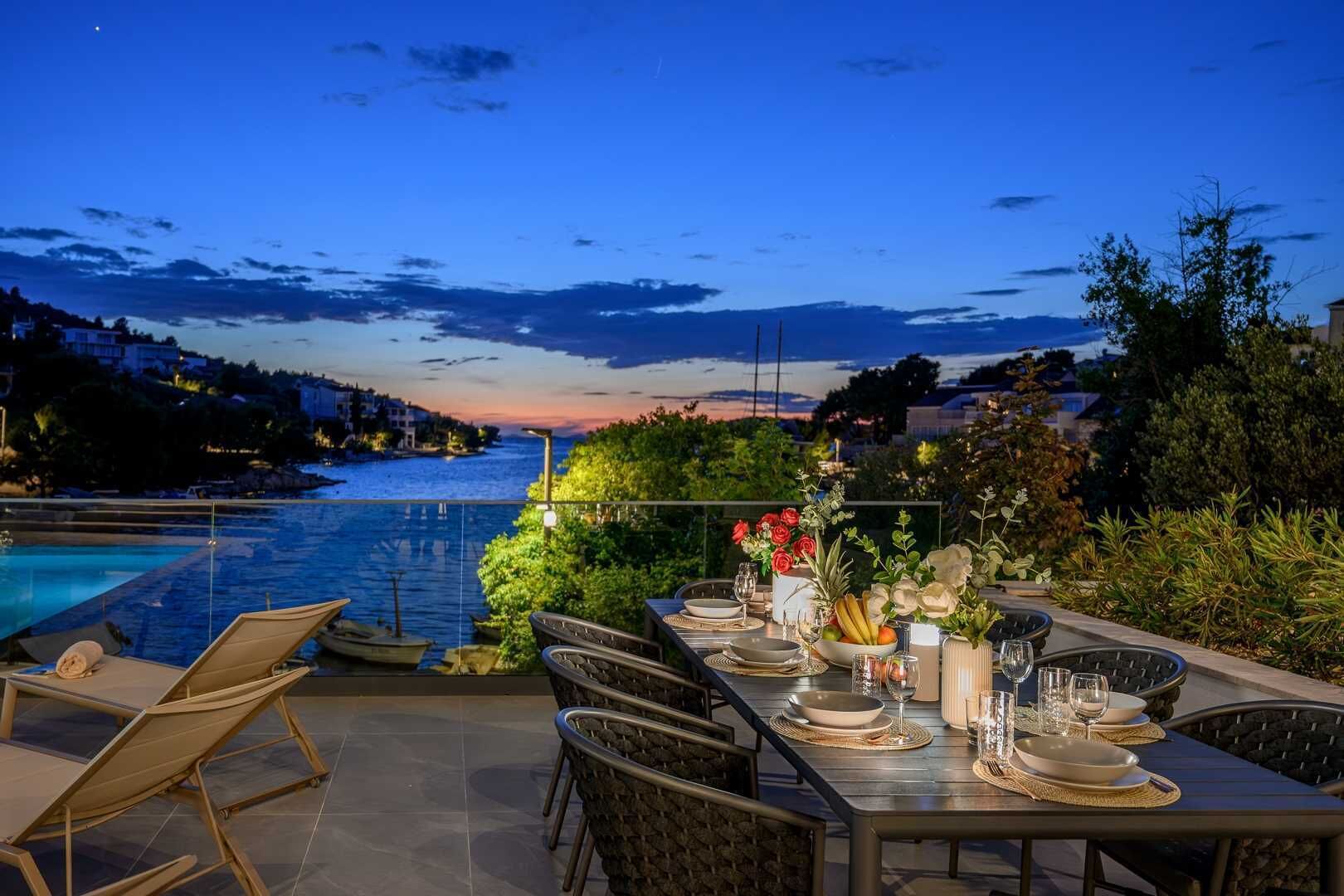 An outdoor dining area with a view of a body of water and a sunset.