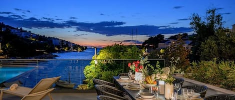 Un espacio de comedor al aire libre con vista al agua y al atardecer.