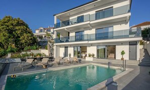 A modern two-story building with a swimming pool, outdoor seating, and a staircase leading to the upper floor. - Villa Between Seas with Pool (Ražanj)