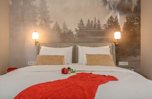 A hotel room with a bed, two bedside lamps, a red rose, and a forest-themed wall tapestry. - Villa Between Seas with Pool (Ražanj)