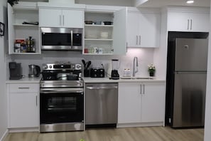 Eine moderne Küche mit Edelstahlgeräten, weißen Schränken und einem eingebauten Backofen.