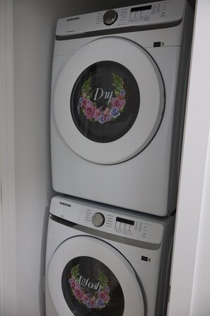 A front view of a Samsung washing machine with a floral decal on the door. - Entire guest apartment 1BR- close to West Edmonton Mall for long/short term rent (Edmonton)
