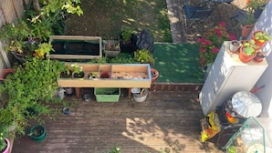 A wooden deck with raised garden beds, potted plants, and a small table. - London Southeast Modern Stay (London)