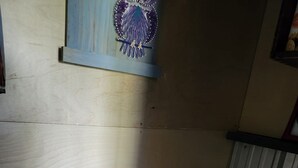 Pieni, käytännöllinen kylpyhuone, jossa on wc, puulattia ja seinälle kiinnitetty hylly, jonka päällä on koriste-esine.