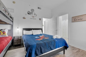 A bedroom with a bed, a nightstand, a Mickey Mouse pillow, and a wall with a fire alarm and Mickey Mouse stickers. - Cozy 2-bedroom condo in welcoming Kissimmee with AC and gym access (Kissimmee)