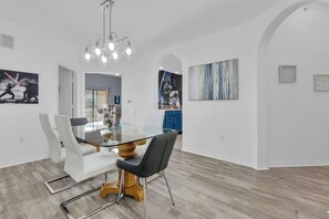 Ein Essbereich mit einem Glastisch, weißen Stühlen und einer Chandelier.