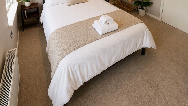 A neatly arranged bedroom with a bed, bedside tables, a mirror, and a window. - Double Bedroom with Kitchenette (London)