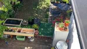 A wooden deck with a raised garden bed, potted plants, and a small table. - Double Bedroom with Kitchenette (London)