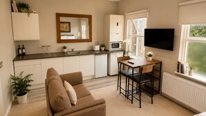 A compact living space with a kitchenette, a sofa, a dining area, and a bed. - Double Bedroom with Kitchenette (London)