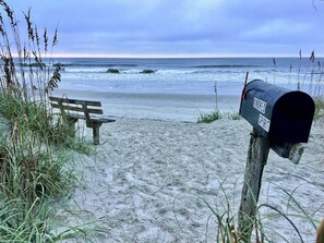 Eine Strandansicht mit einem Briefkasten mit der Aufschrift 'MARRED SAID' und einer Bank.
