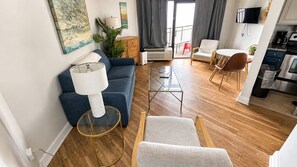 Een moderne woonkamer met een bank, een glazen salontafel en een eethoek met stoelen.