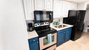 A kitchen with white upper cabinets, a black microwave, a stainless steel stove, a sink, and a black refrigerator. - Captivating Oceanview Balcony & Resort Pools (Myrtle Beach)