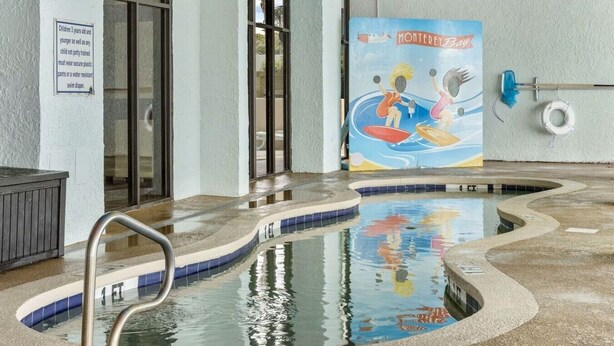 An indoor pool with a mural, a lifeguard stand, and a sign indicating pool rules. - Captivating Oceanview Balcony & Resort Pools (Myrtle Beach)