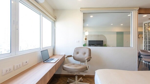 Un dormitorio con una cama, un escritorio con una computadora portátil, una silla y una ventana.