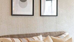 Un sofá con almohadones a rayas y de colores, una obra de arte enmarcada en la pared y un revestimiento de pared con textura.