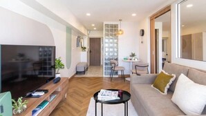 Una sala de estar moderna con un televisor de pantalla plana, un sofá, una mesa de centro y una zona de comedor con sillas.
