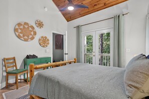 A bedroom with a bed, a wooden headboard, a green dresser, a chair, and a ceiling fan. - Gem of the Mountain -Cozy Cabin Retreat Near Helen (Sautee Nacoochee)