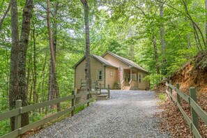 A cabin with a gravel driveway and wooden fence, surrounded by dense forest. - Gem of the Mountain -Cozy Cabin Retreat Near Helen (Sautee Nacoochee)