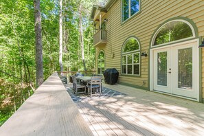 A wooden deck with a table and chairs, a covered grill, and a house with arched windows and a balcony. - Gem of the Mountain -Cozy Cabin Retreat Near Helen (Sautee Nacoochee)