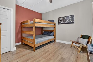 A bunk bed in a room with wooden flooring, a door, and a wall with a nature-themed artwork. - Gem of the Mountain -Cozy Cabin Retreat Near Helen (Sautee Nacoochee)