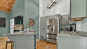 A modern kitchen with granite countertops, stainless steel appliances, and a wooden ceiling. - Gem of the Mountain -Cozy Cabin Retreat Near Helen (Sautee Nacoochee)